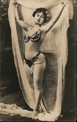 A woman dressed in beads holds draping cloth above her head Postcard