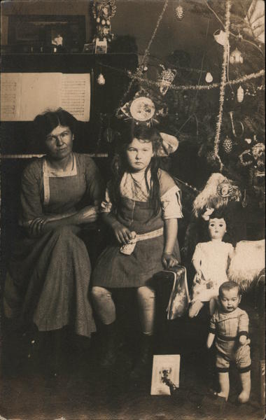 A Little Girl and Woman Next to Dolls Under a Christmas Tree