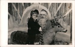 A Little Girl Sitting on a Reindeer Next to Santa Postcard