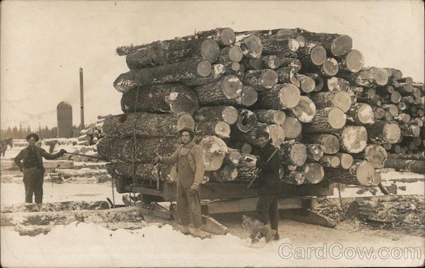 Three Men Standing By a Large Stack of Lumber Logging