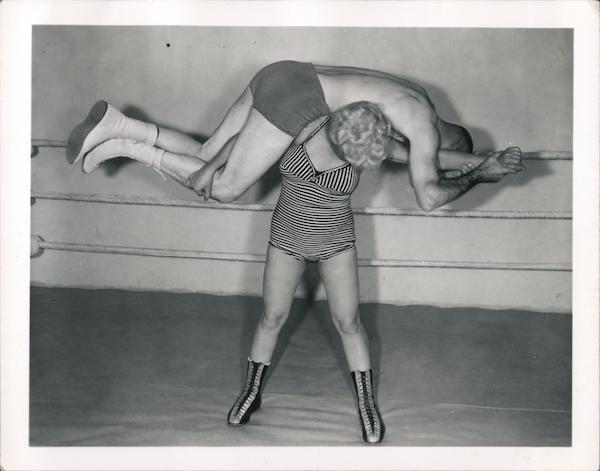 Female wrestler holding man across shoulders
