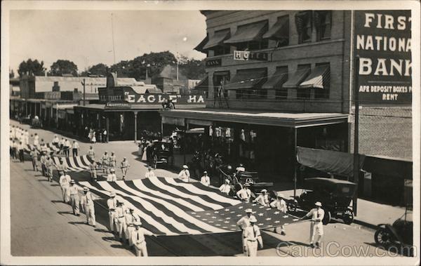 Parade of three large U.S. Flags carried by servicemen.