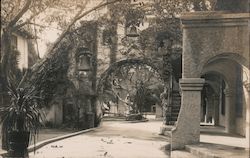 Arched walkway and street with church bells Postcard