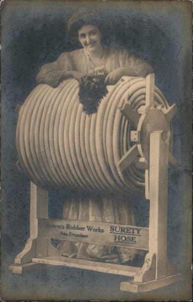Surety Hose, Bowers Rubber Works. Woman standing next to large roll of hose on spindle San Francisco