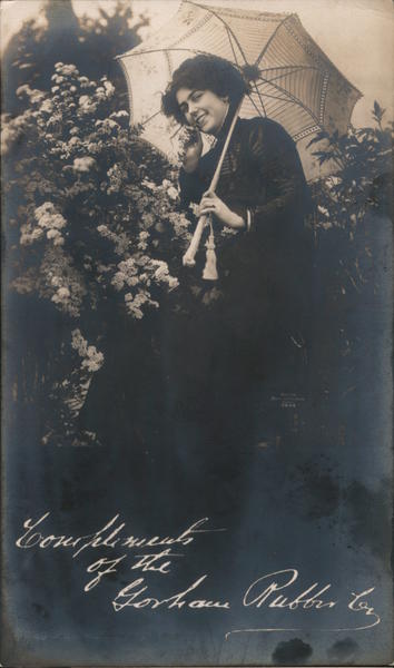 Woman sitting among flowers holding a parasol - Gorham Rubber Co. San Francisco California