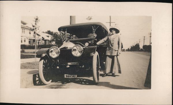Woman standing next to convertible Car, large headlights, license 80374