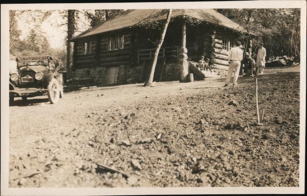 Log cabin, man taking picture of kids sitting on step, car Siberia California