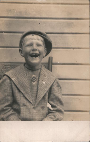 Laughing boy sitting in chair missing teeth Children