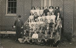 Class photo by a brick building Postcard