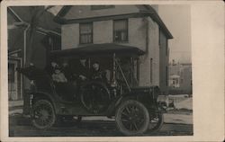 Family in open car in front of house Postcard