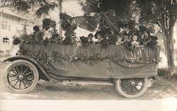 Parade car covered in roses, children riding Postcard