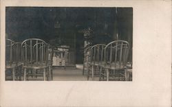 Wooden chairs and rack of books set up for an event Postcard