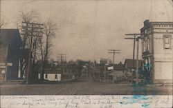 Street view, men outside building on porch, dirt road, telephone poles, houses Postcard