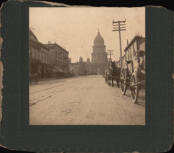 Horse-drawn traffic on a dirt street with Courthouse in distance San Francisco California