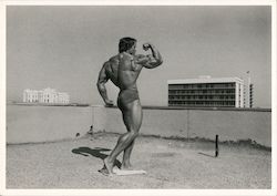 Arnold Schwarzenegger body building pose on rooftop, 1973 Postcard