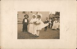 Children parading in costumes. Astoria Soda Works in background. Postcard