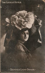 The Latest Style - "Trimmed Lamp Shade" A photo of a woman displaying a large, ornate hat Postcard