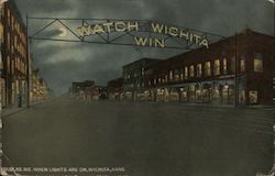 Douglas Ave when light are on, Wichita, Kans. - A street with store lights and a sign that says, "Watch Wichita Win" Postcard