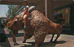 Bison - Two girls climb on a bison sculpture on the Mall at The Landing Postcard