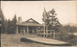 Rustic cabin in the woods with flag in front Postcard