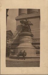 soldiers sitting crosslegged under imposing statue Postcard