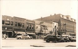 Storefronts from 40s, vintage cars parked on street Postcard