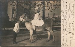 B&W Photo of Little Girl Atop a Pony While Little Boy Holds the Reins In Residential Neighborhood Postcard