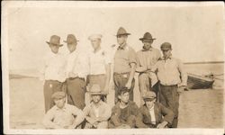 Group of men poses with boat and ocean in background Postcard