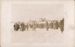 Large group of men in snow outside of town Postcard