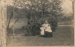A woman and Two Young Children in Front of Bushes Postcard