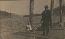Man standing on dock pulling baby in a cart Postcard
