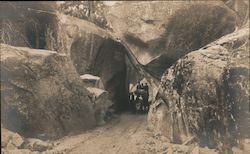 Group of travelers on horse-drawn wagon pose under massive granite overhang pass Postcard