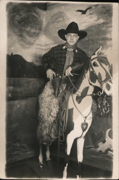 Man Dressed as Cowboy Wooly Chaps, Holding Pistol on Fake Horse
