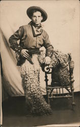 Man Dressed as a Cowboy Wearing Wooly Chaps and Holding a Pistol Postcard