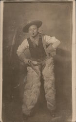 Man Dressed as a Cowboy Wearing Wooly Chaps and Holding a Pistol Postcard