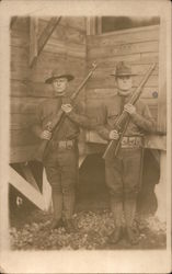 two soldiers posed with rifles in front of a building. Postcard