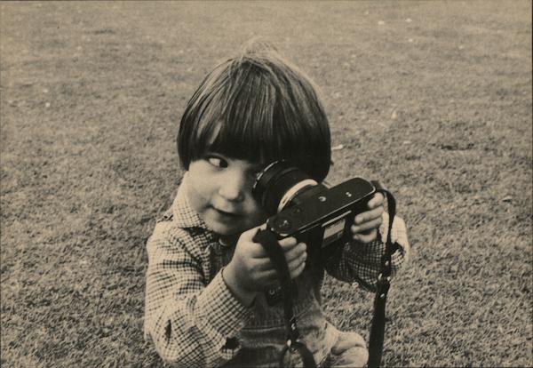 Young Photographer - A boy holding a camera holds the lens up to his eye